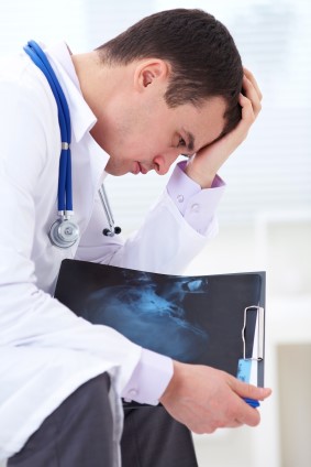 Home Page image A doctor holding his head in his hands.