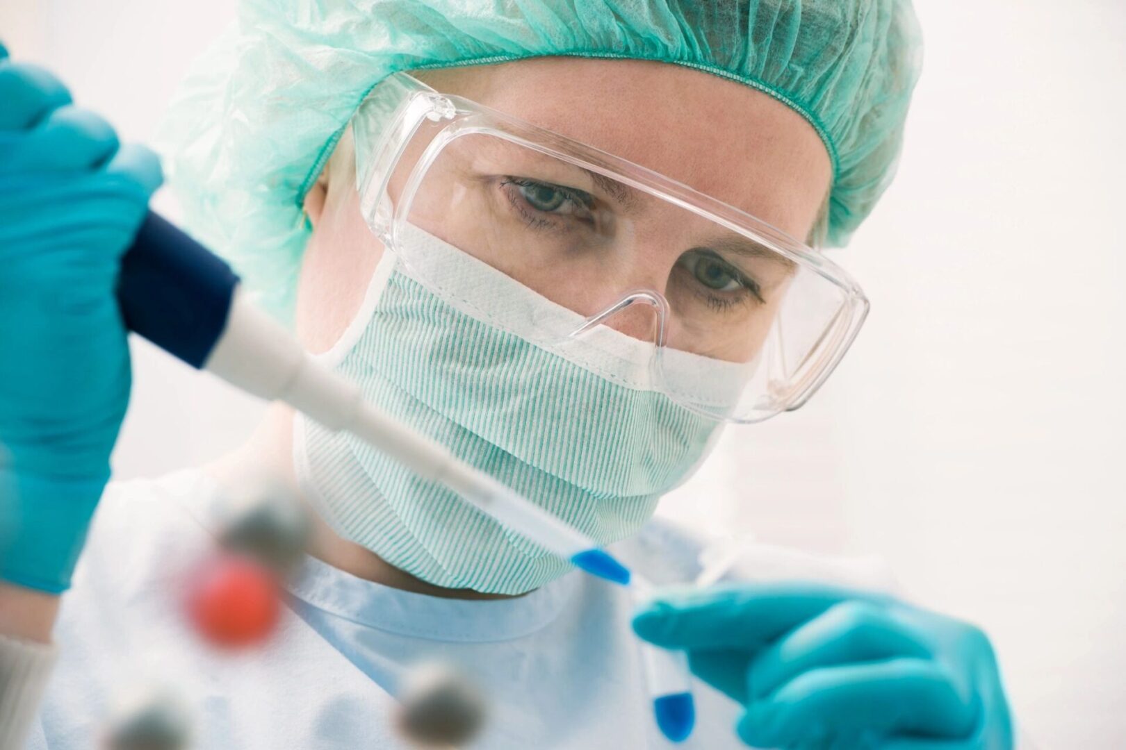 fm=f_13258 A woman in blue lab coat and goggles holding a tube.